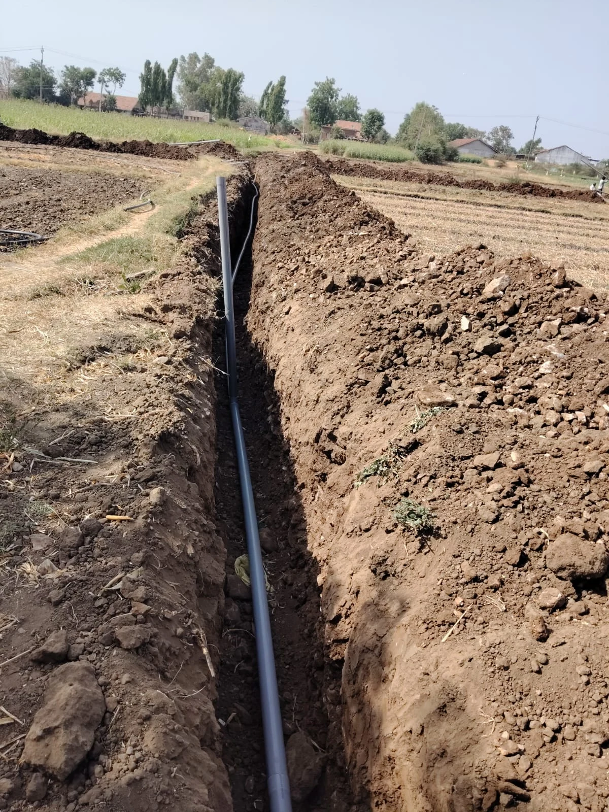 An irrigation pipeline laid in a long trench across a farm